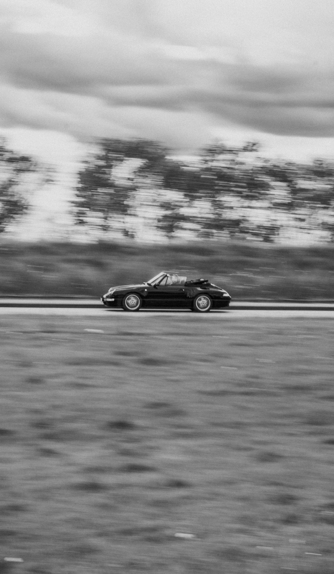 grayscale photo of black coupe on road