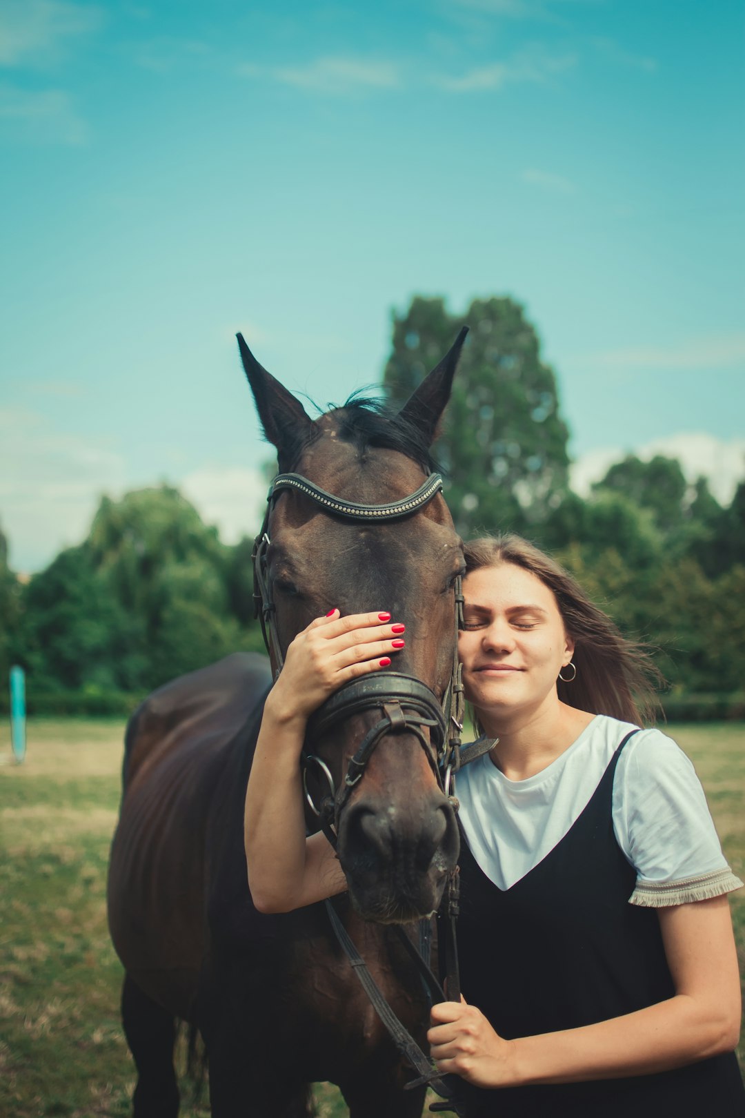 woman in white shirt standing beside brown horse during daytime