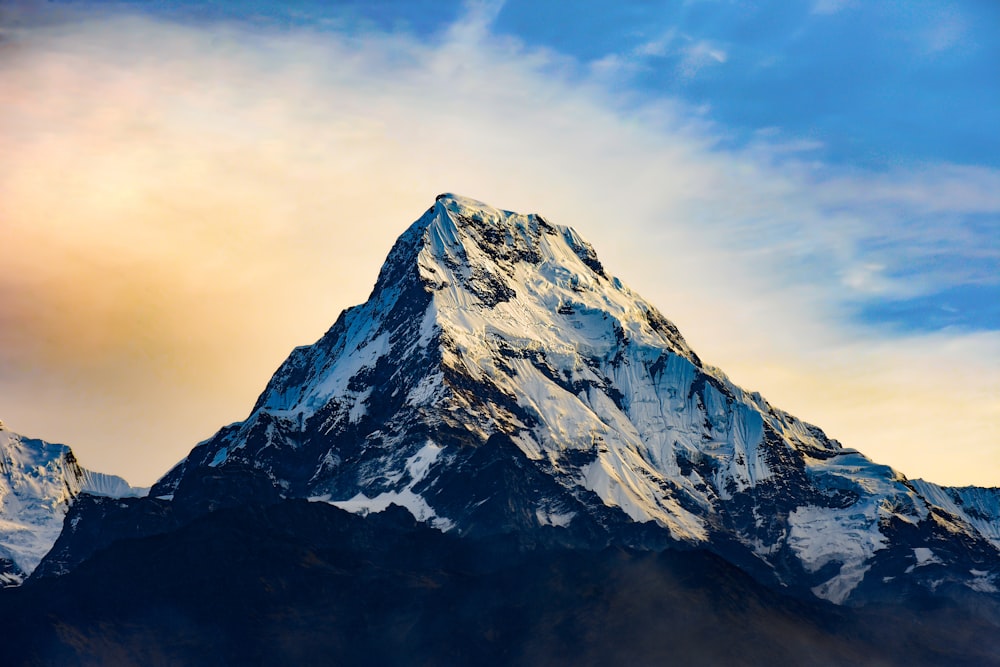 montagne enneigée sous un ciel nuageux pendant la journée