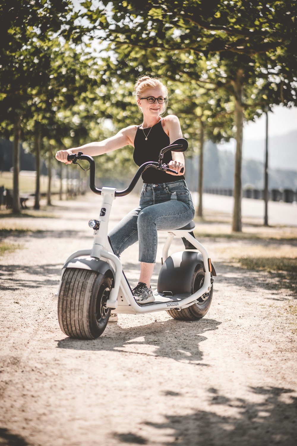 Frau in schwarzem Hemd und blauer Jeans fährt tagsüber auf weißem und schwarzem Motorrad