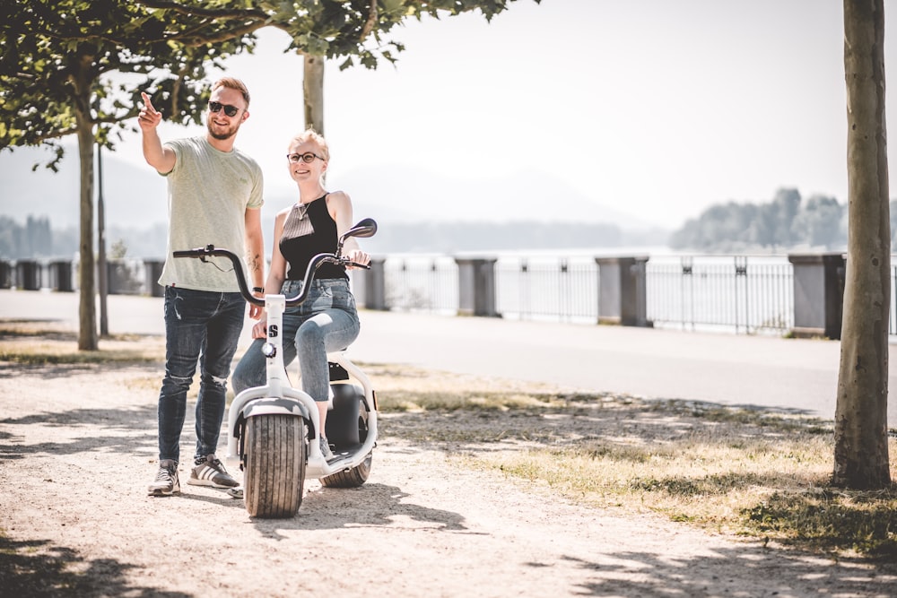 man and woman riding motorcycle on brown sand during daytime