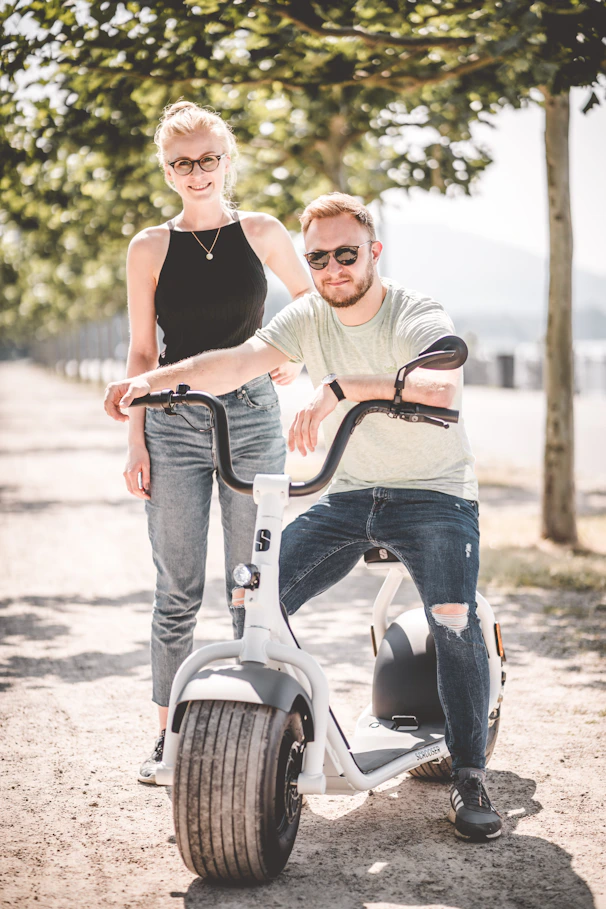 man and woman riding on white and black scooter during daytime