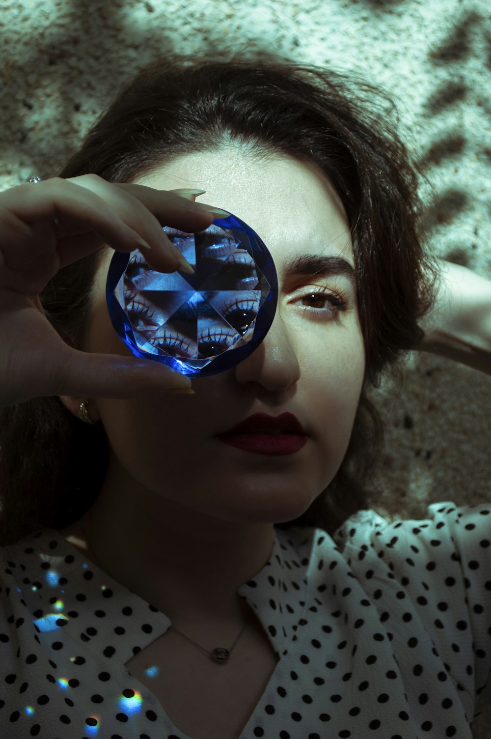 girl in white and black polka dot shirt holding blue glass ball