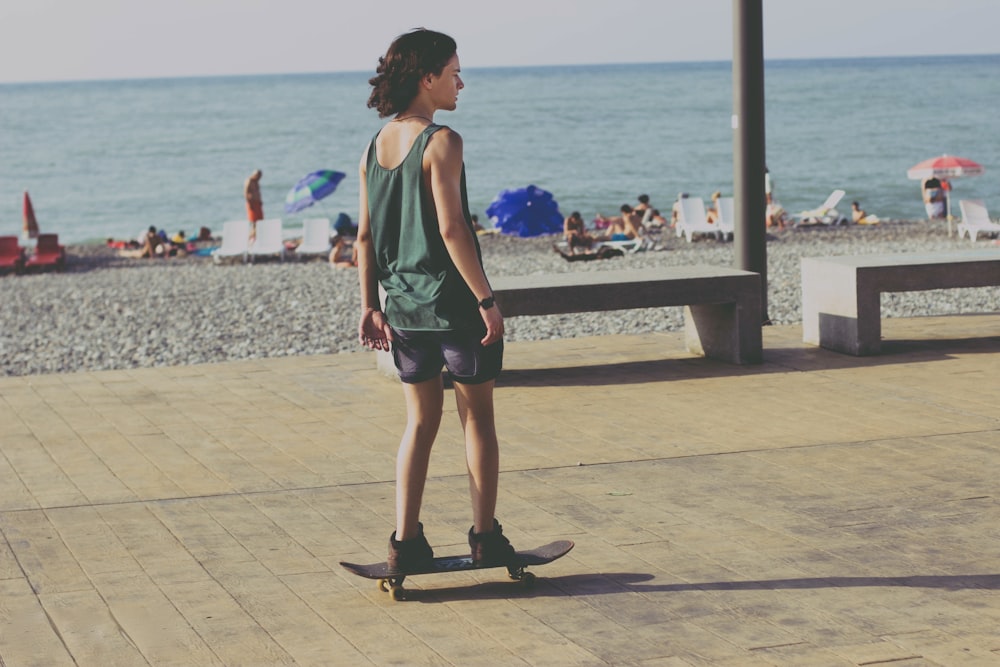 woman in green tank top and black shorts standing on gray concrete dock during daytime