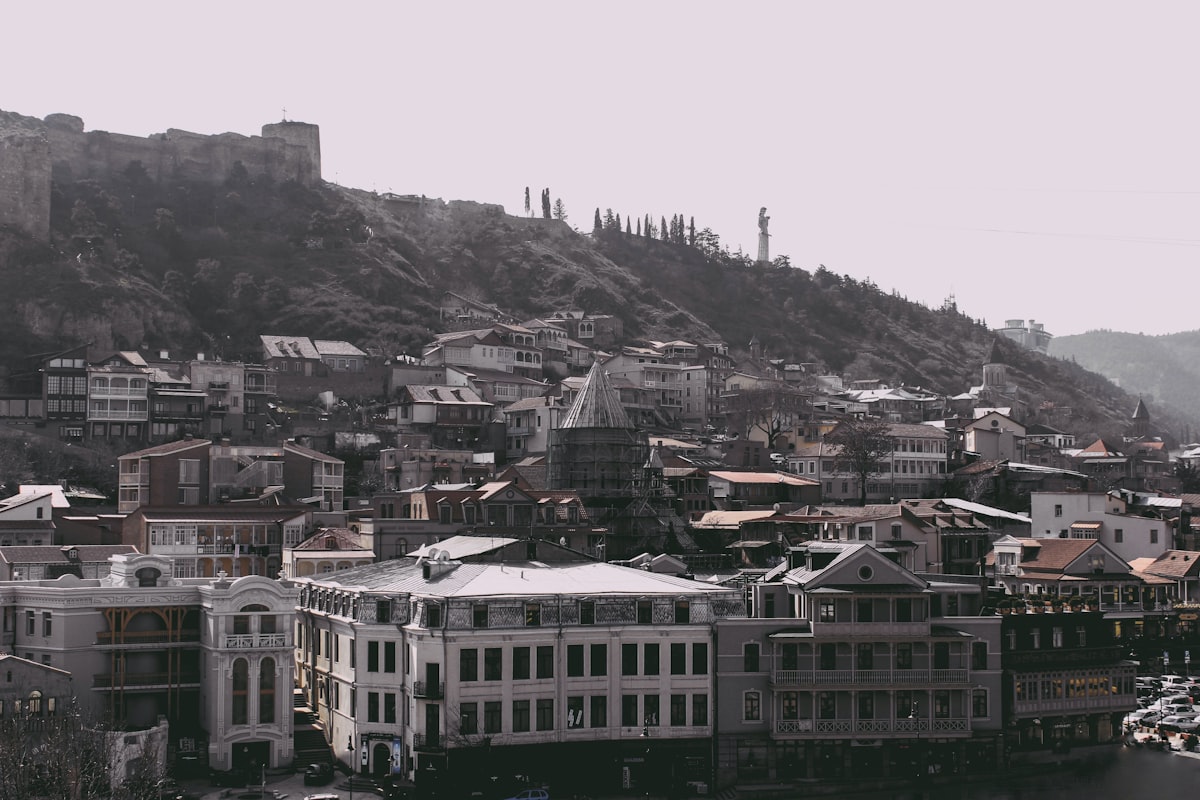 Old Tbilisi Abanotubani — aerial view of the old quarter with red-tiled roofs and wooden balconied houses below Narikala Fortress