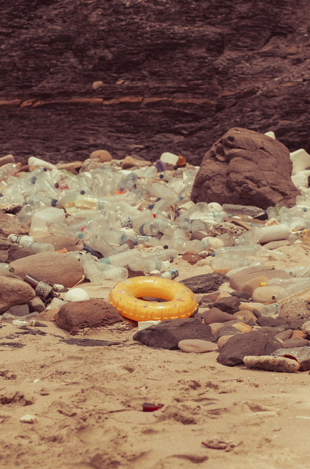 yellow inflatable ring on brown rocky shore