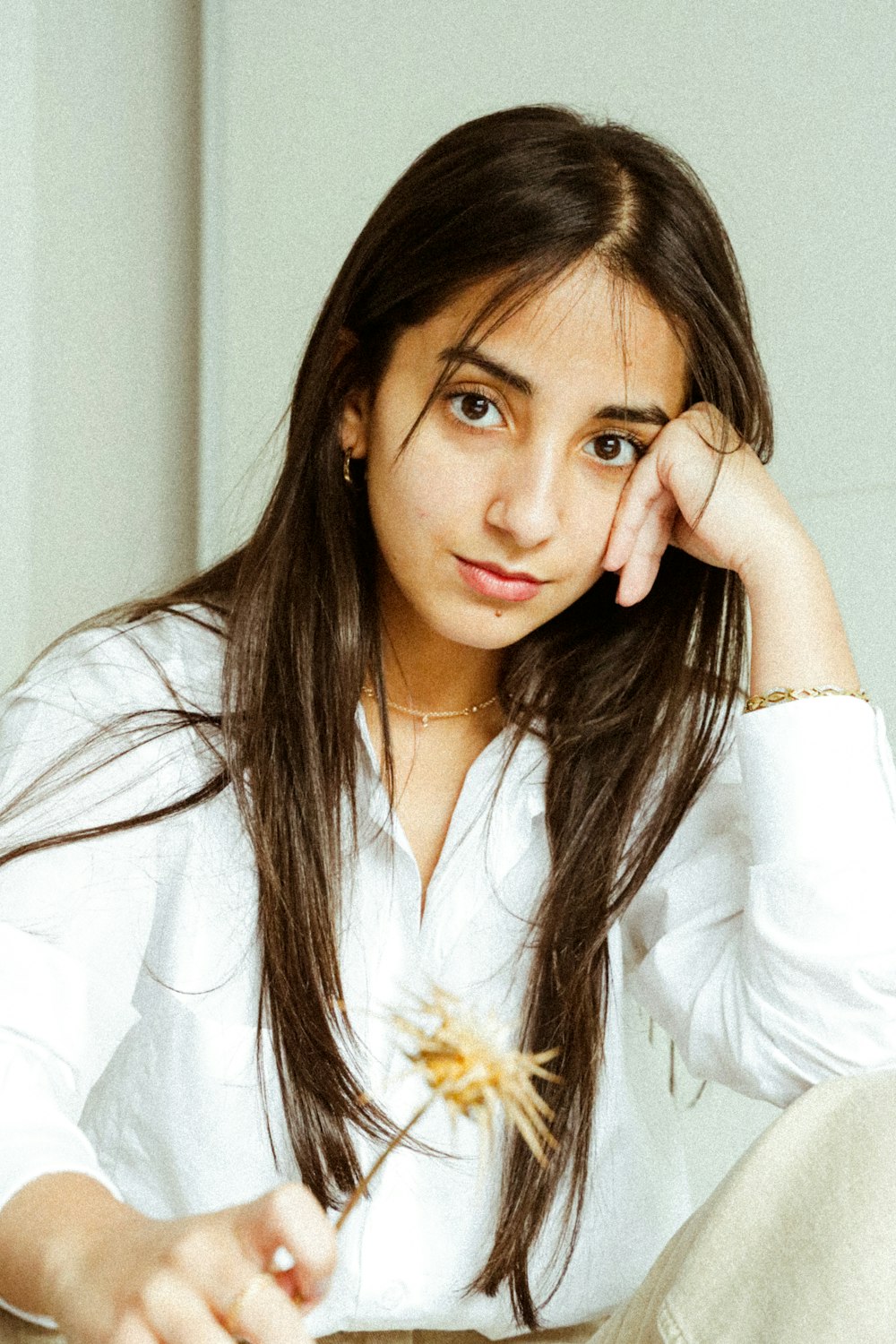 woman in white long sleeve shirt holding yellow flower