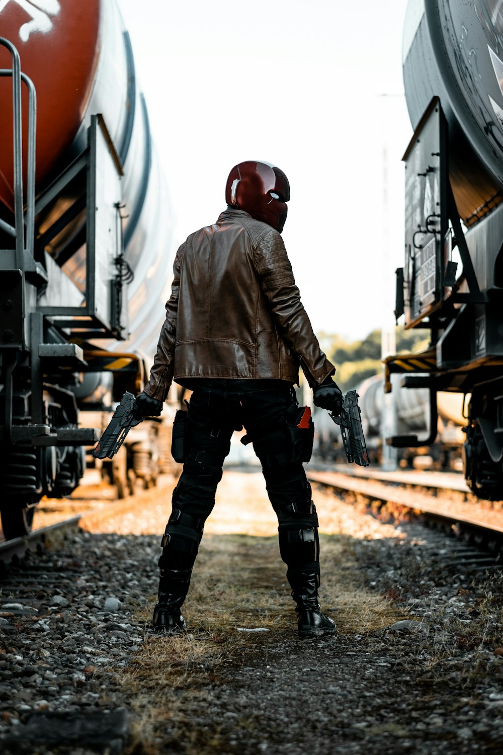 homme en veste en cuir marron et pantalon noir portant un casque noir