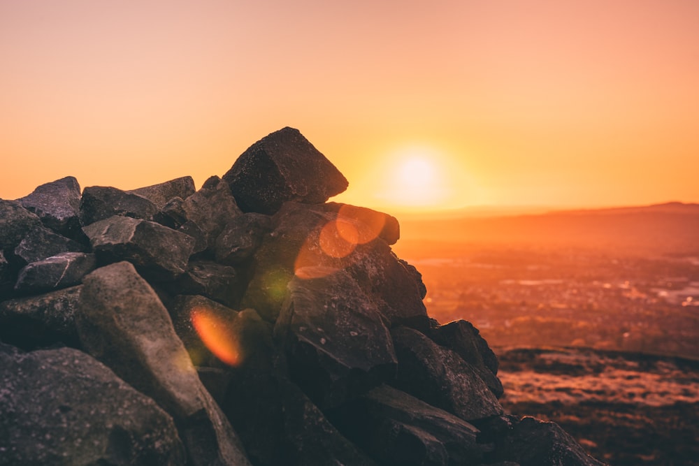 black and brown rocks near body of water during sunset