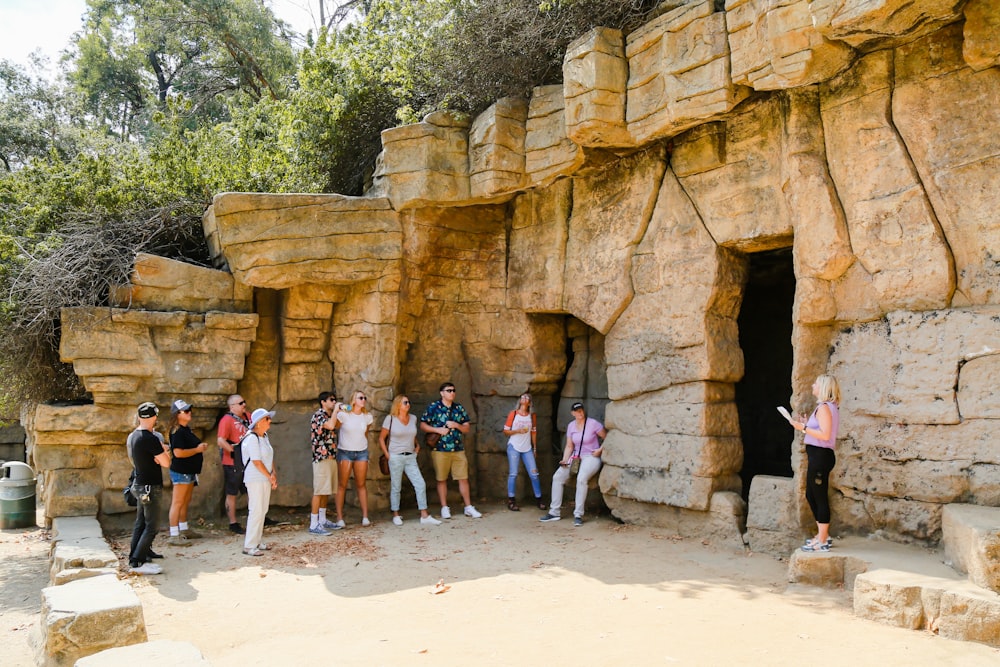 people standing near brown rock formation during daytime