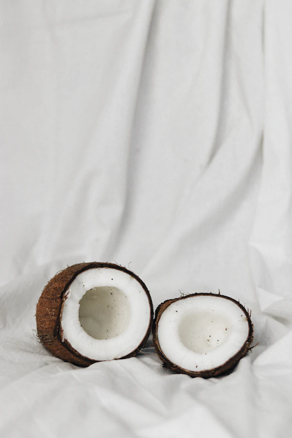 Coco partido y aceite en cuencos sobre charola de madera