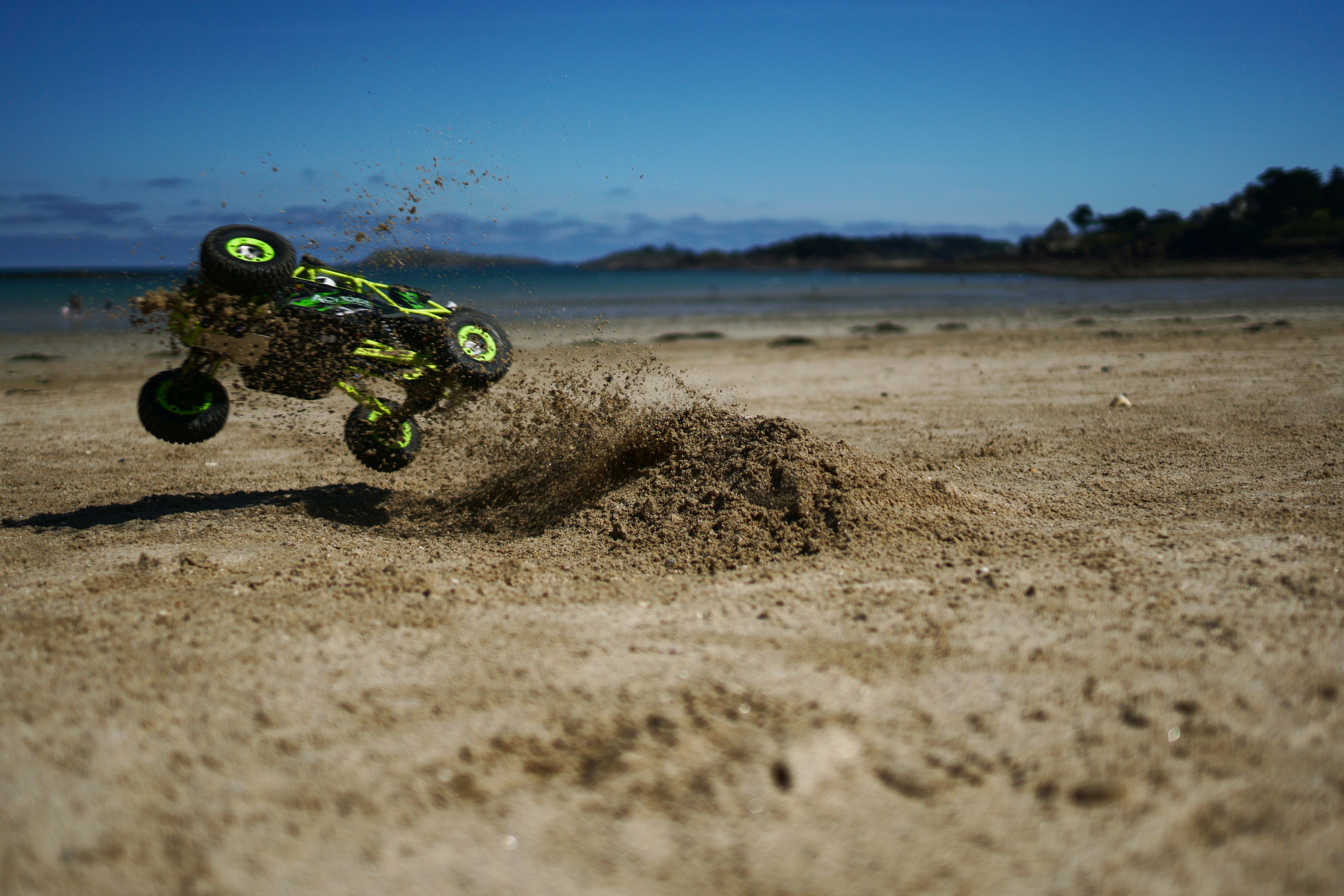 green and black motocross dirt bike on brown sand during daytime