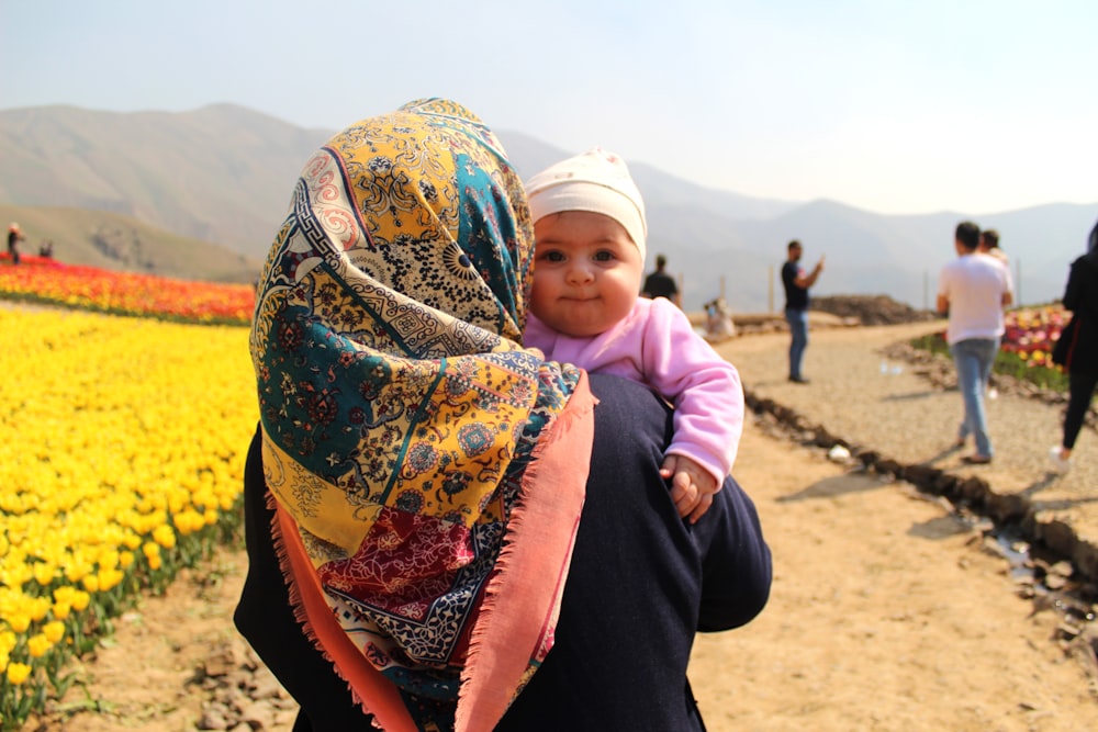 woman in black long sleeve shirt carrying baby in pink jacket during daytime