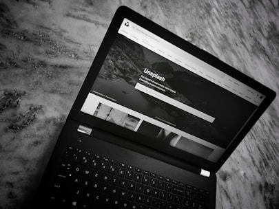 A sleek laptop displaying a portfolio of premium domain names on a black background.