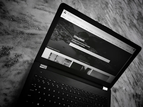 A sleek laptop screen displaying a clean, modern image search interface with vibrant photos in a masonry grid layout.