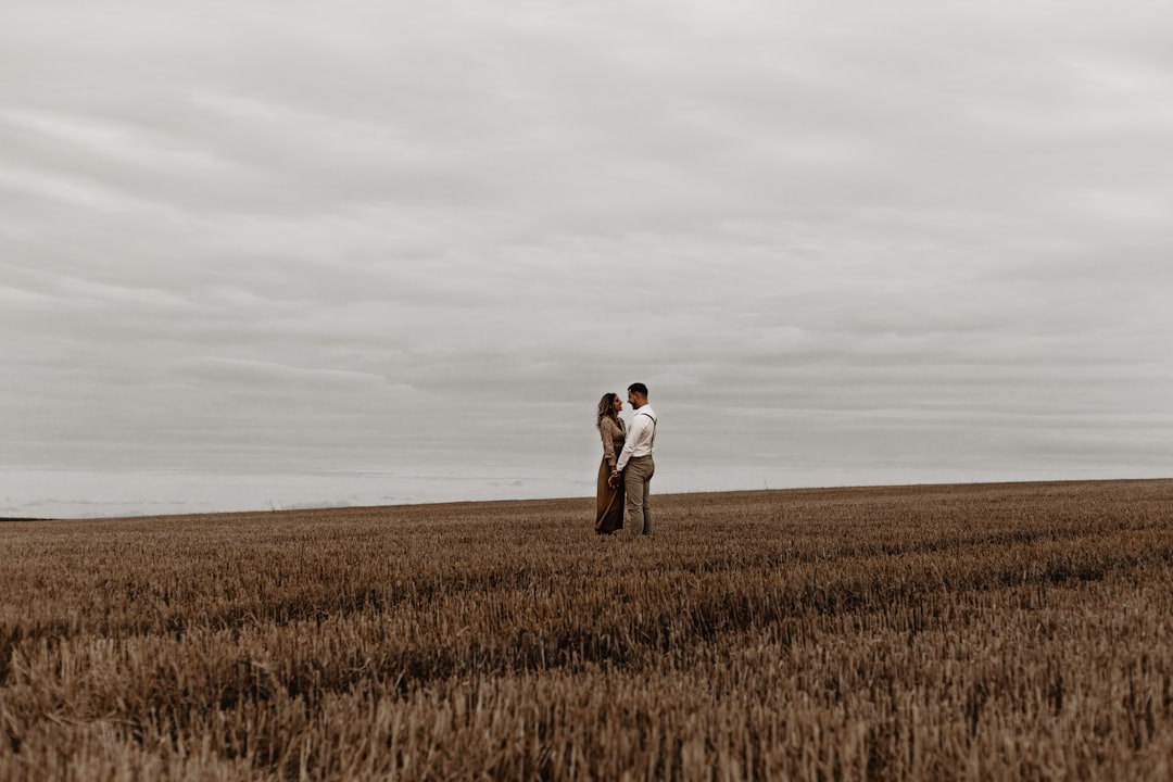 man and woman kissing on brown grass field during daytime