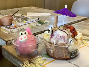 Surf-shaped spoons arranged artistically beside tropical fruits and bowls of ice cream