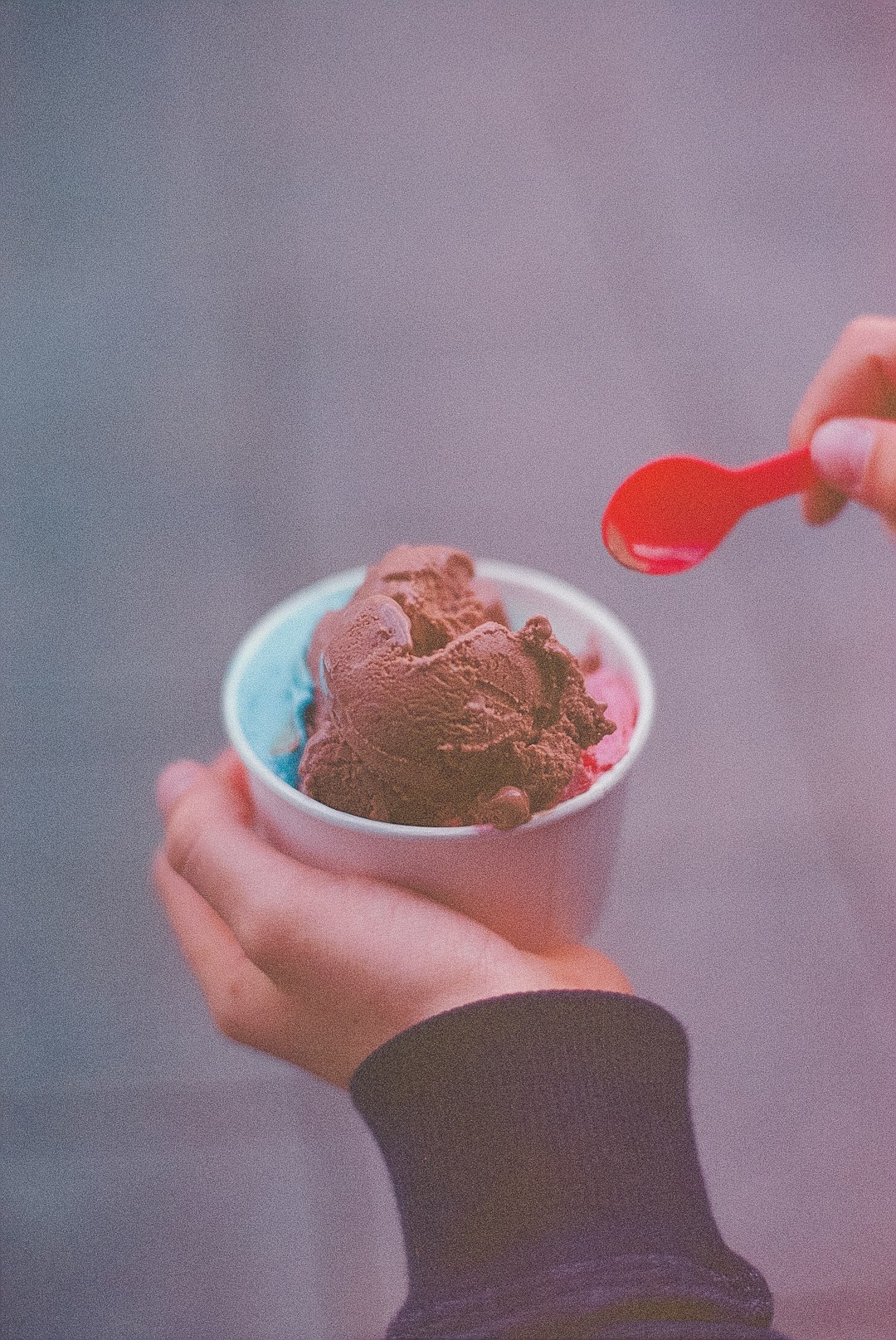 person holding ice cream with red spoon