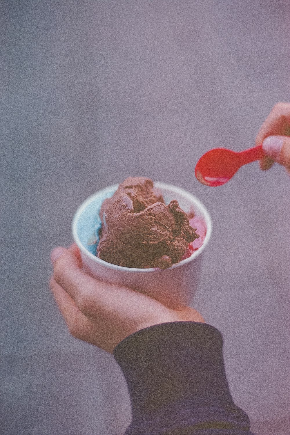 persona sosteniendo helado con cuchara roja
