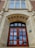 A grand, old architectural building entrance featuring a large wooden door with multiple panels and ornate stone carvings around the arch. Above the door are decorative windows with diamond-shaped glass panes, and the words 'Arts Building' etched into the stone. The structure is made of a combination of brick and stone, showcasing intricate detailing and craftsmanship.