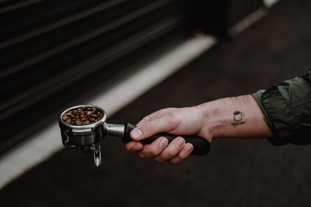 person holding silver and black coffee pot