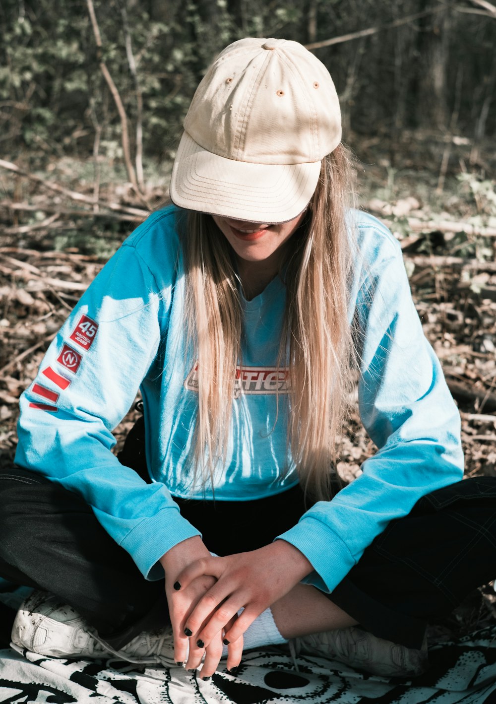 Mujer con chaqueta azul y gorro de punto blanco sentada en el suelo