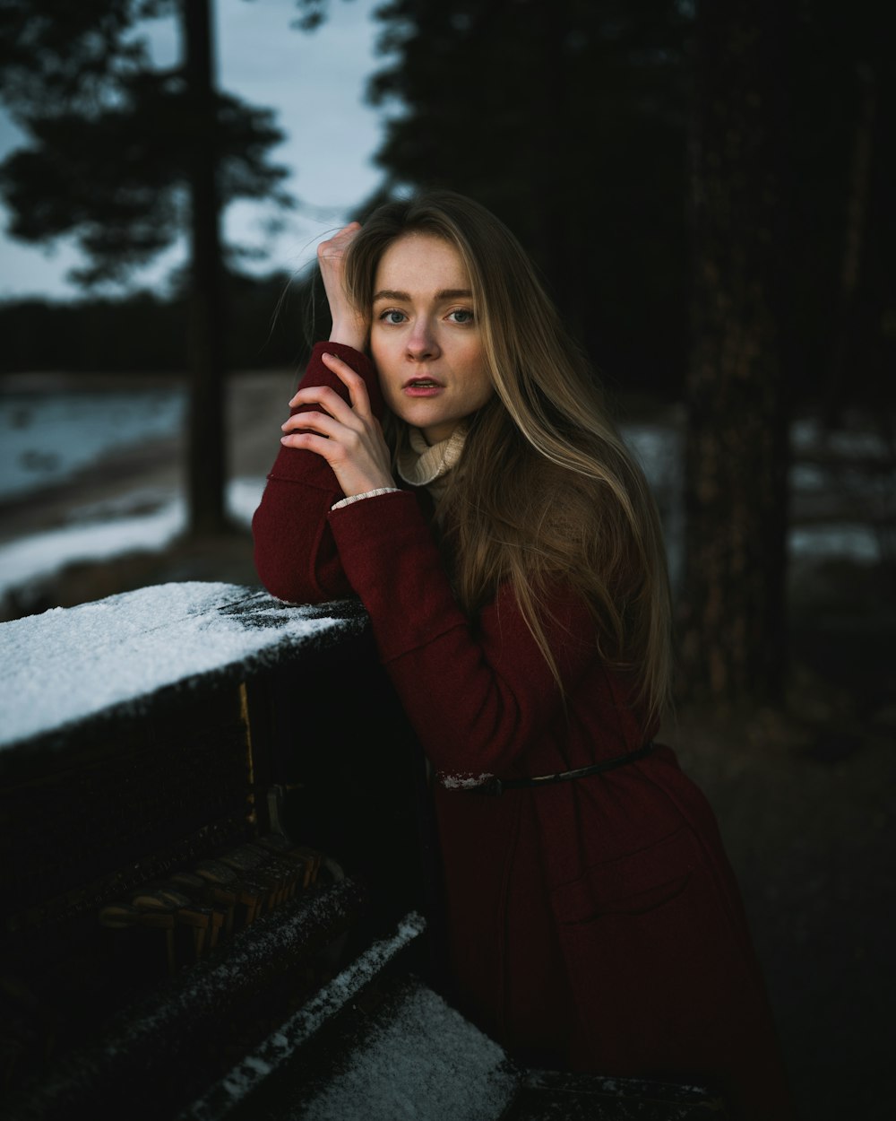 woman in red coat standing near tree during daytime