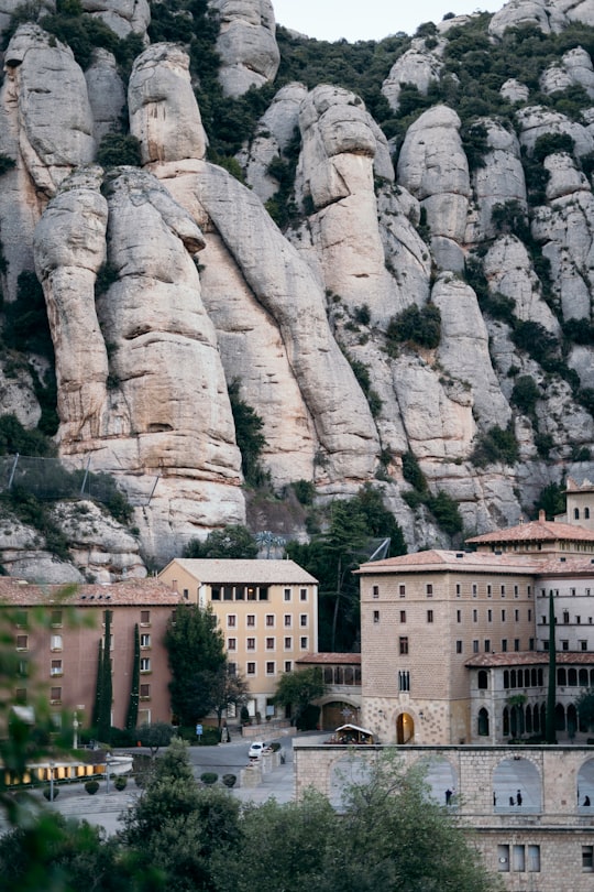 white concrete building near gray rocky mountain during daytime in Santa Maria de Montserrat Abbey Spain