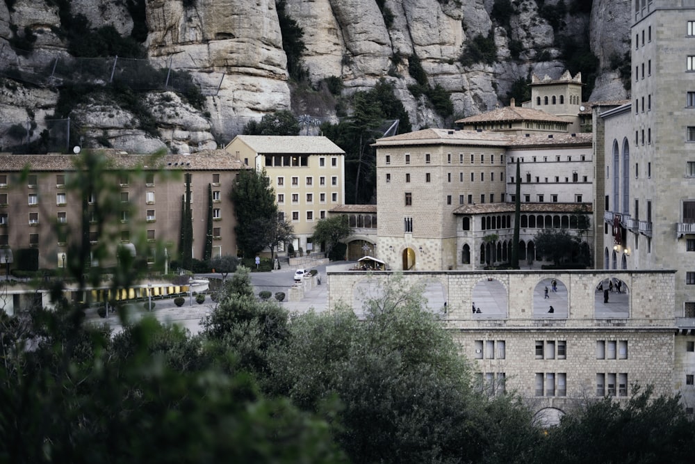 white concrete building near green trees and mountain during daytime