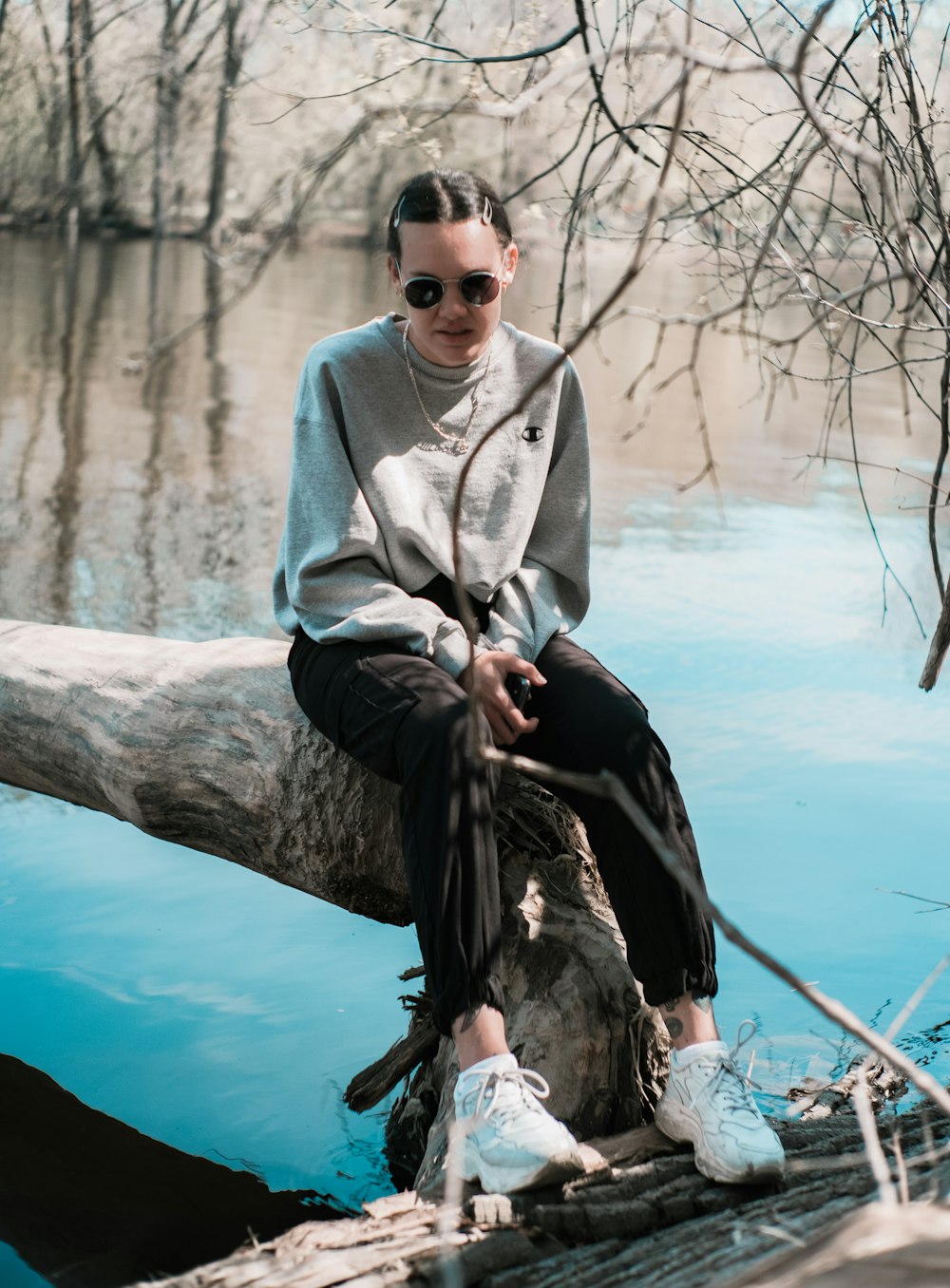 man in gray sweater and black pants sitting on tree branch