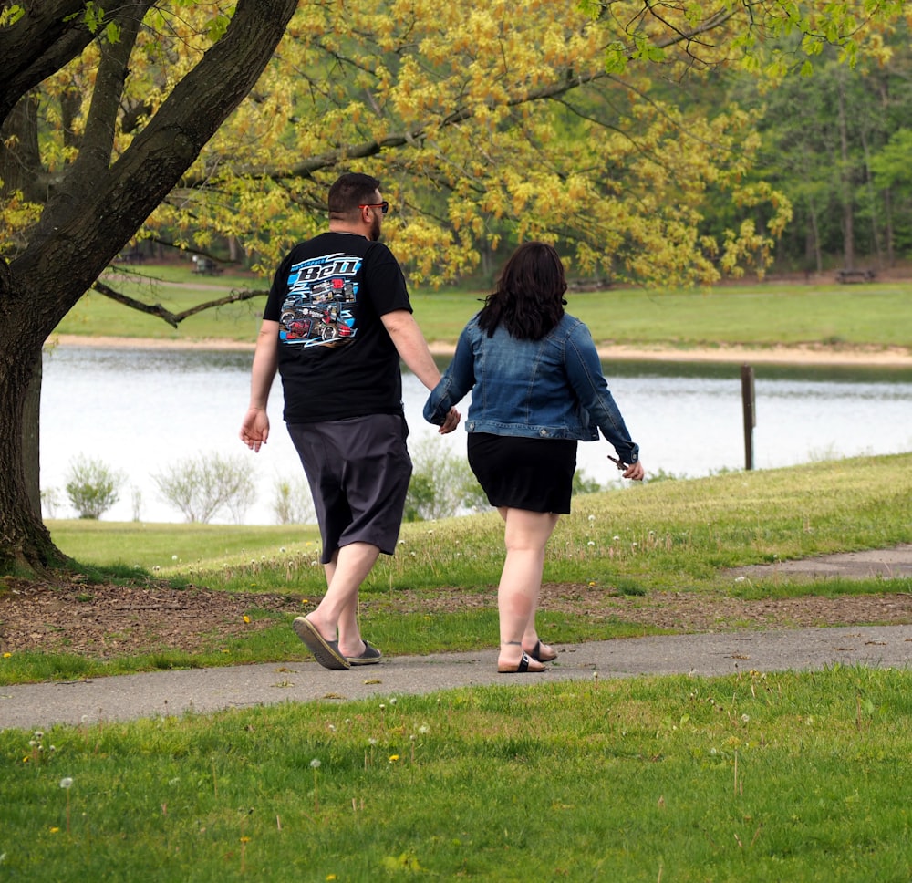 man and woman walking on green grass field during daytime