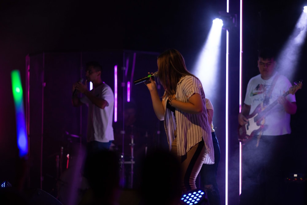 woman in white long sleeve shirt singing on stage