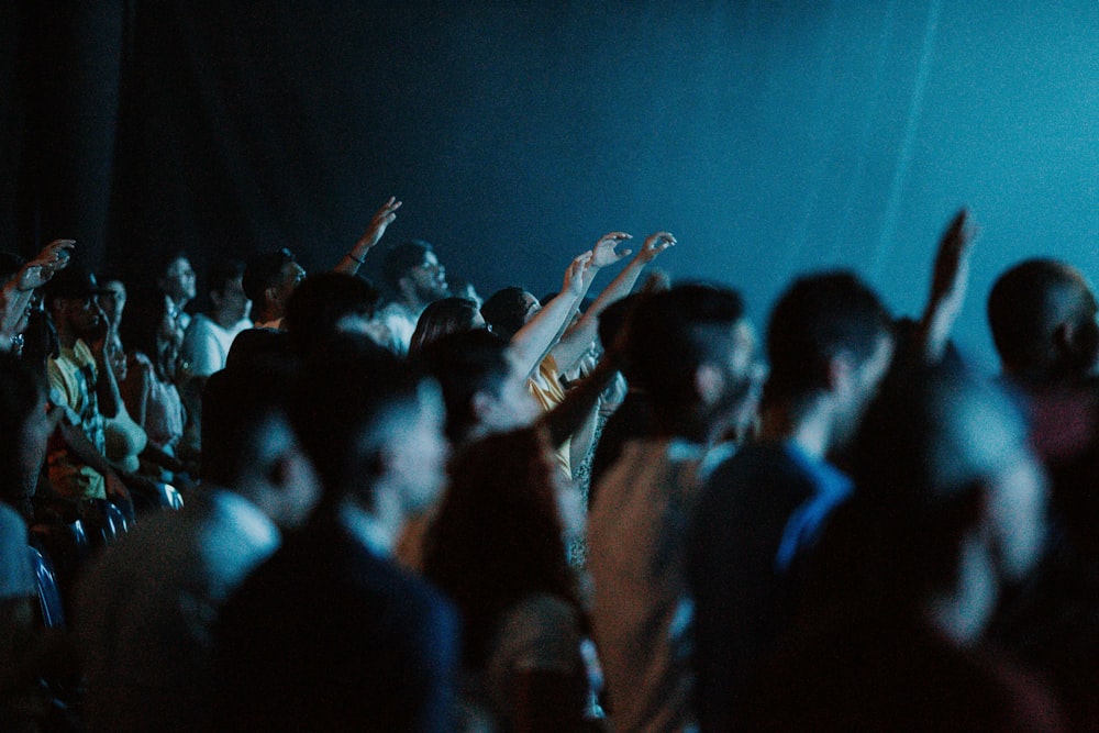 people raising their hands in front of crowd