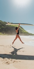 woman in black bikini holding white surfboard on beach during daytime