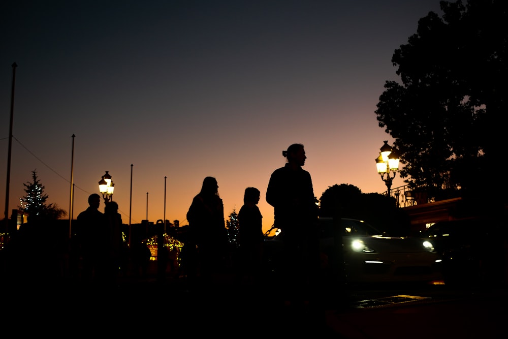 silhouette di persone in piedi sulla strada durante il tramonto