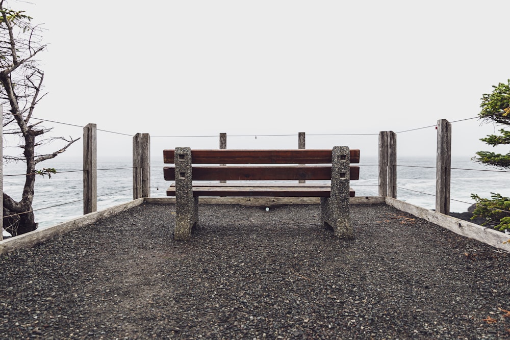 brown wooden bench on brown sand near body of water during daytime