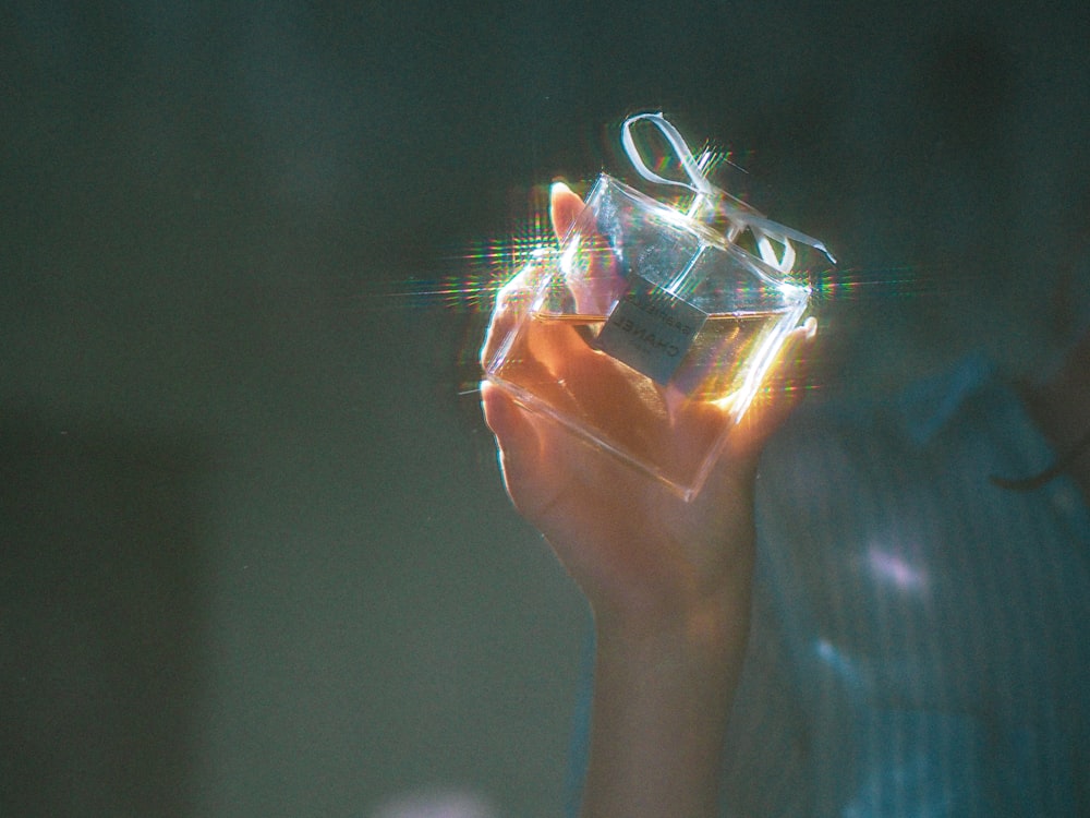 person holding clear glass container