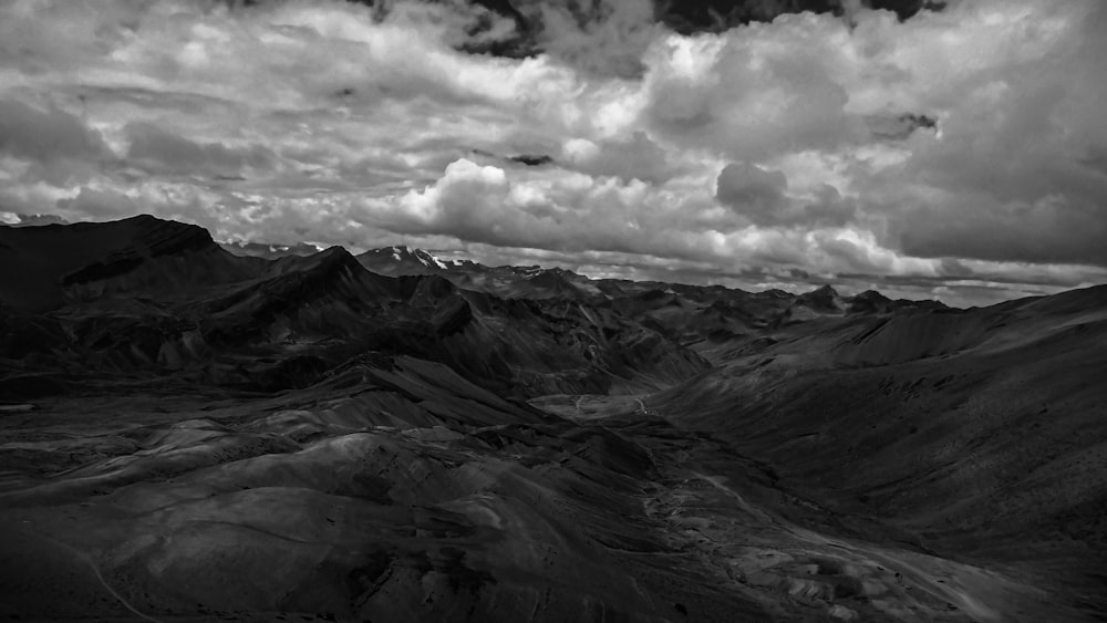 grayscale photo of mountains under cloudy sky