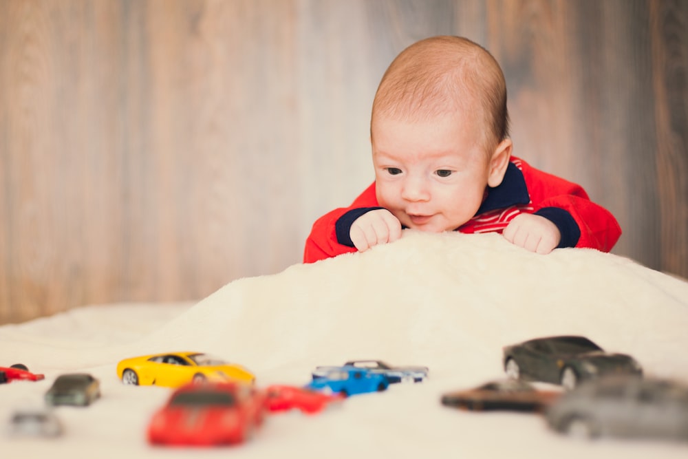 baby in red and white striped long sleeve shirt sitting on white textile