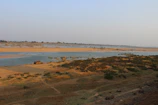Wide shot of a flat terrain with a small river running alongside.