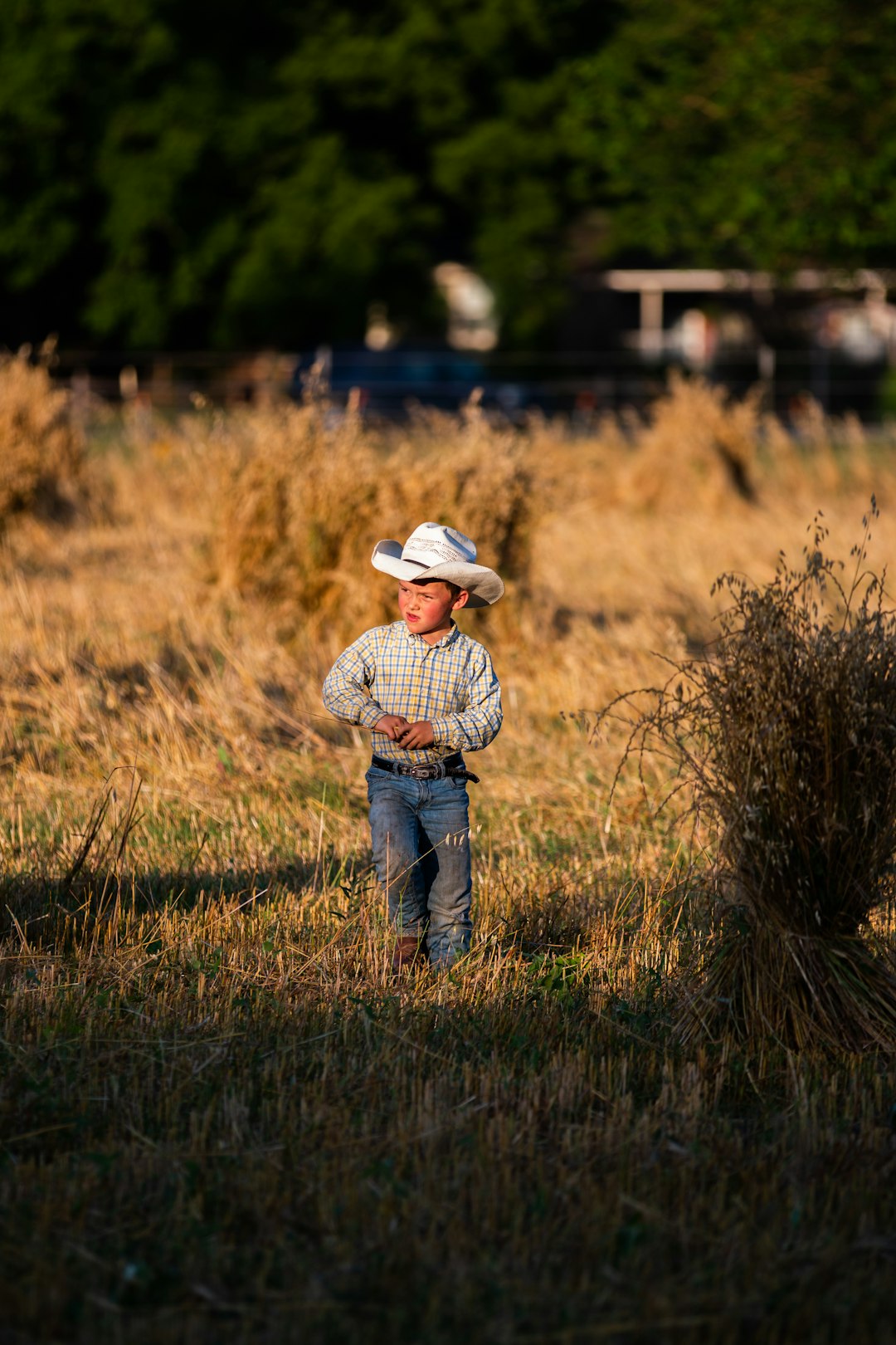 man in white cowboy hat standing on brown grass field during daytime