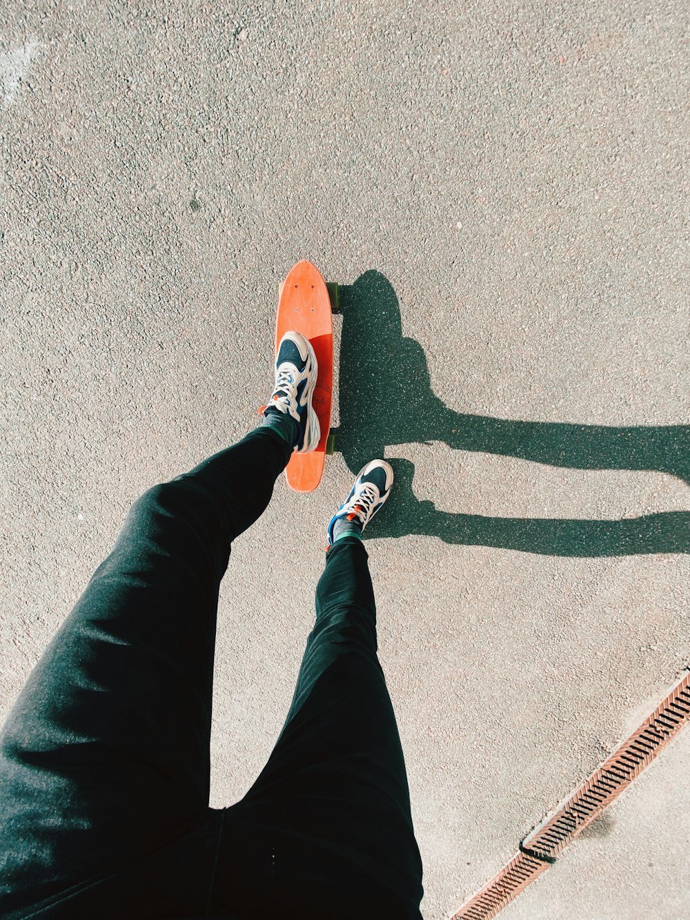 person in black pants and orange and white sneakers