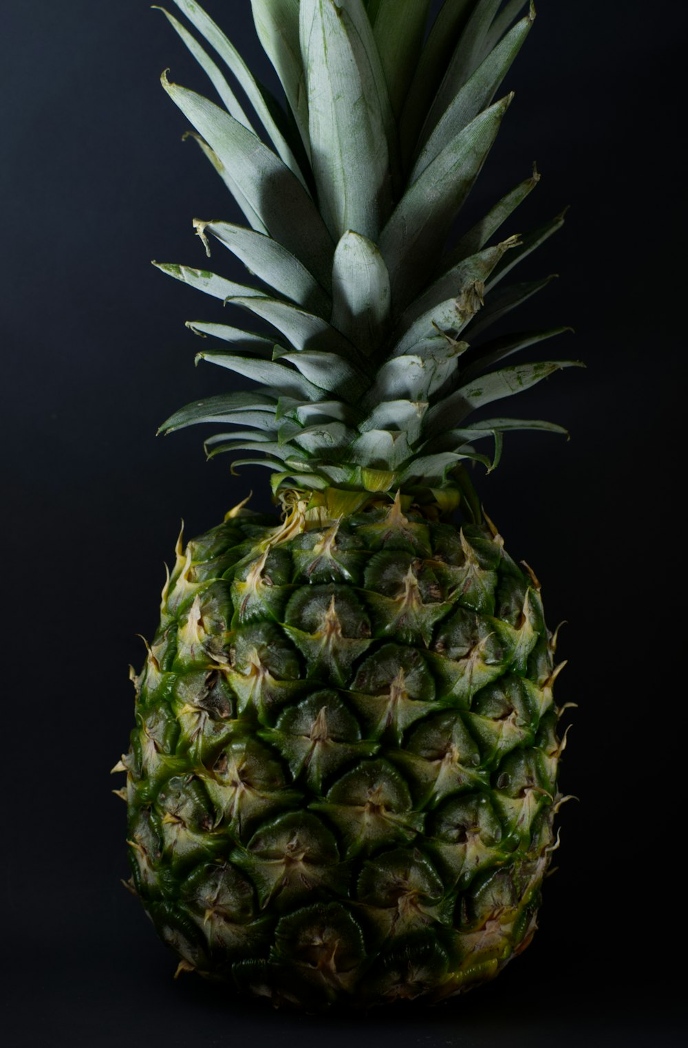 green pineapple fruit on black background