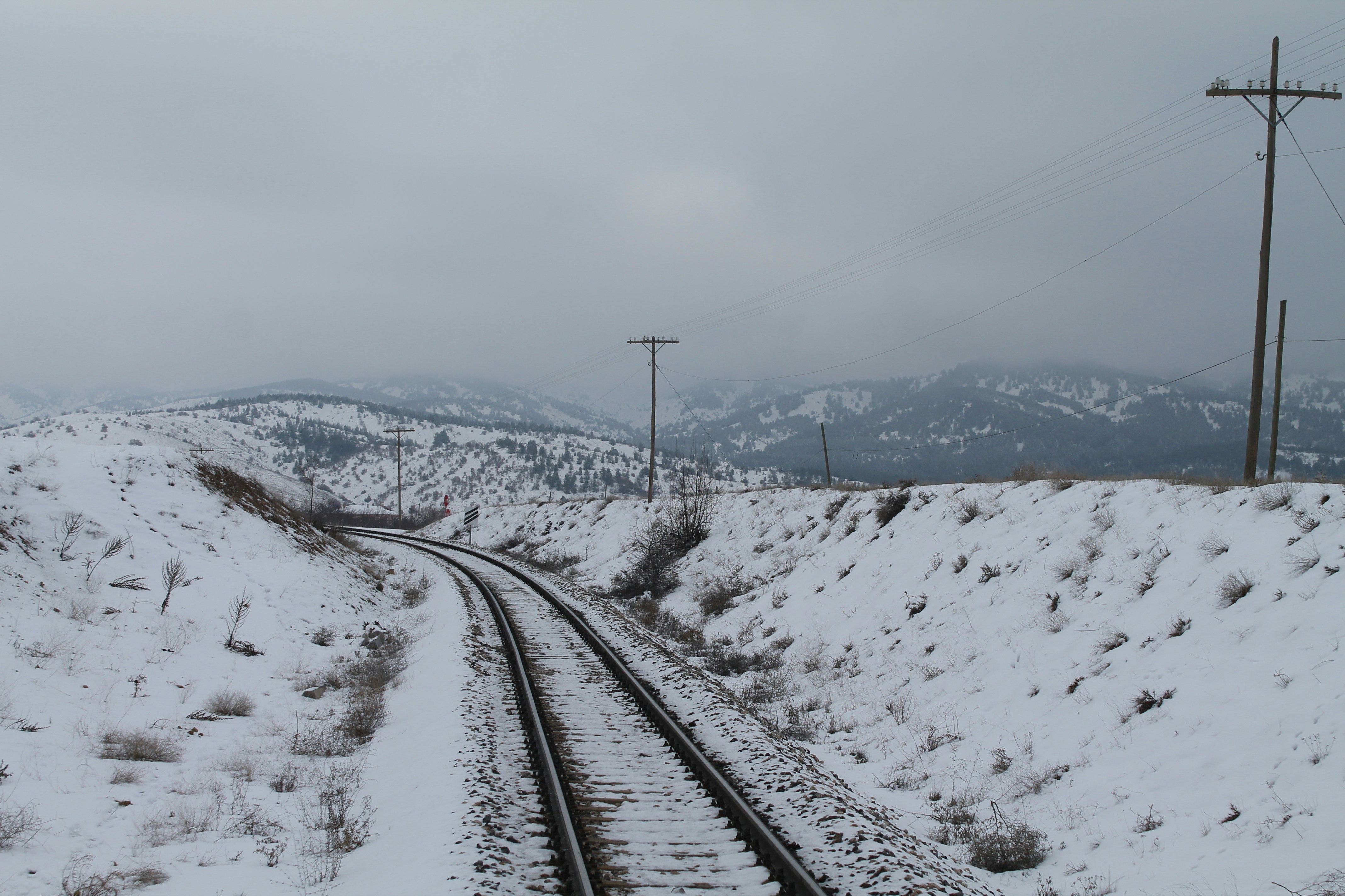 Rail de train noir près d’une montagne enneigée pendant la journée