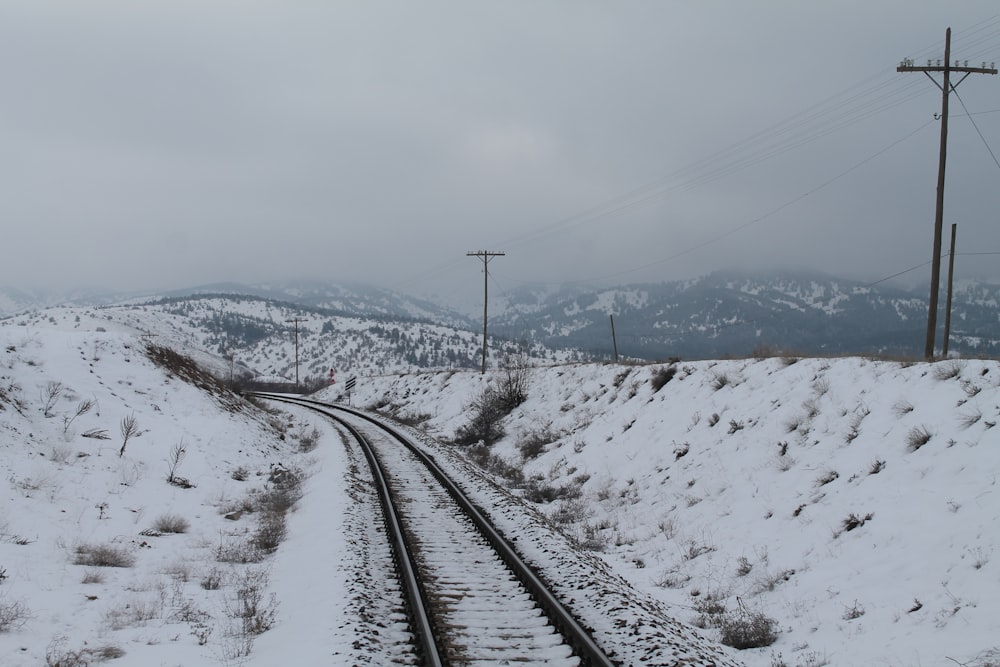 black train rail near snow covered mountain during daytime