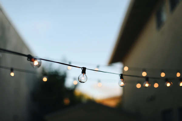 Warm string lights glowing over an outdoor patio at dusk