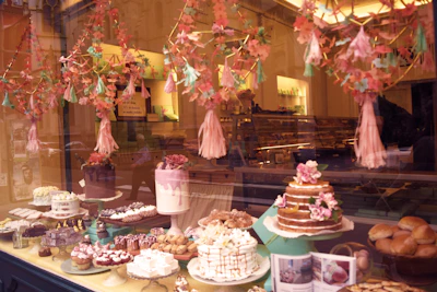 Warm, inviting bakery counter showcasing an array of elegant cakes and brownies under soft lighting.