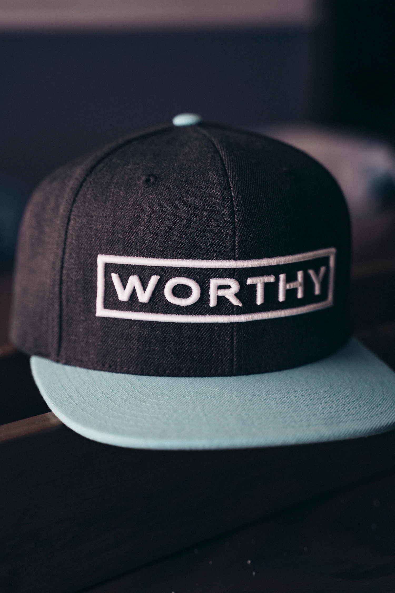 Charcoal snapback with a white WORTHY patch and a mint brim