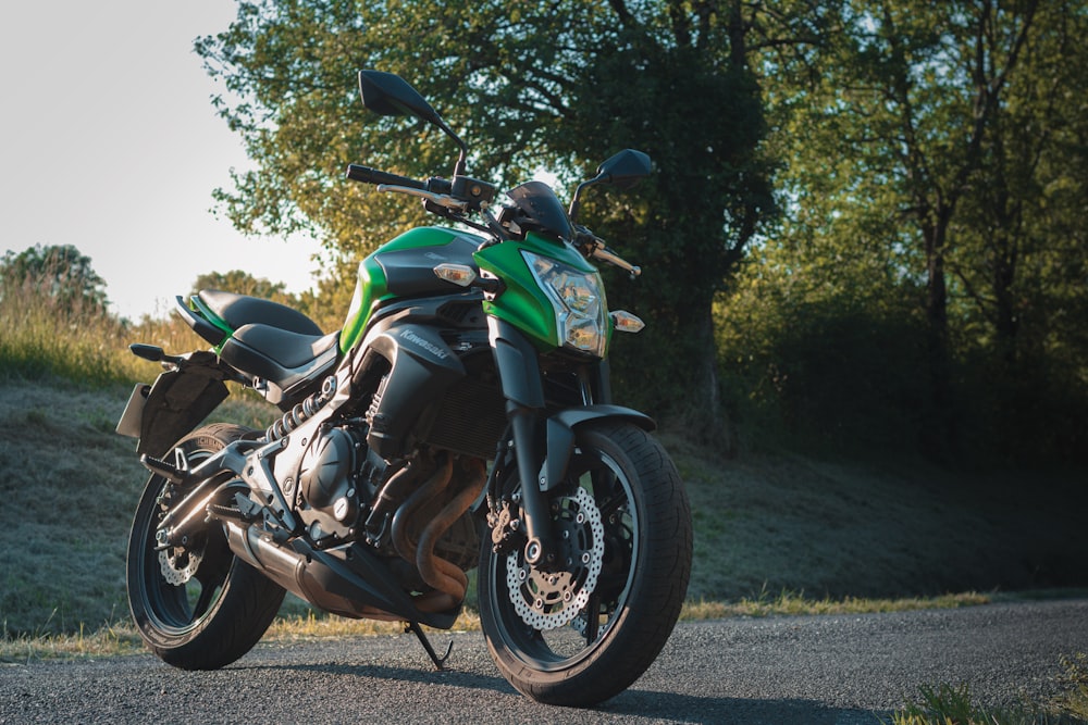 green and black sports bike parked on gray concrete road during daytime