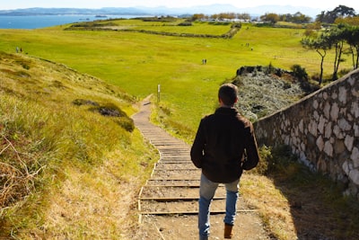 man in black jacket walking on gray concrete pathway during daytime cabo verde teams background